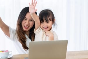 A mother and daughter raise their hands to answer a question while distance learning during a Staycation in New York.