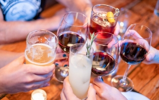 A group of glasses come together in celebration at the table of a Lake George Brewery.