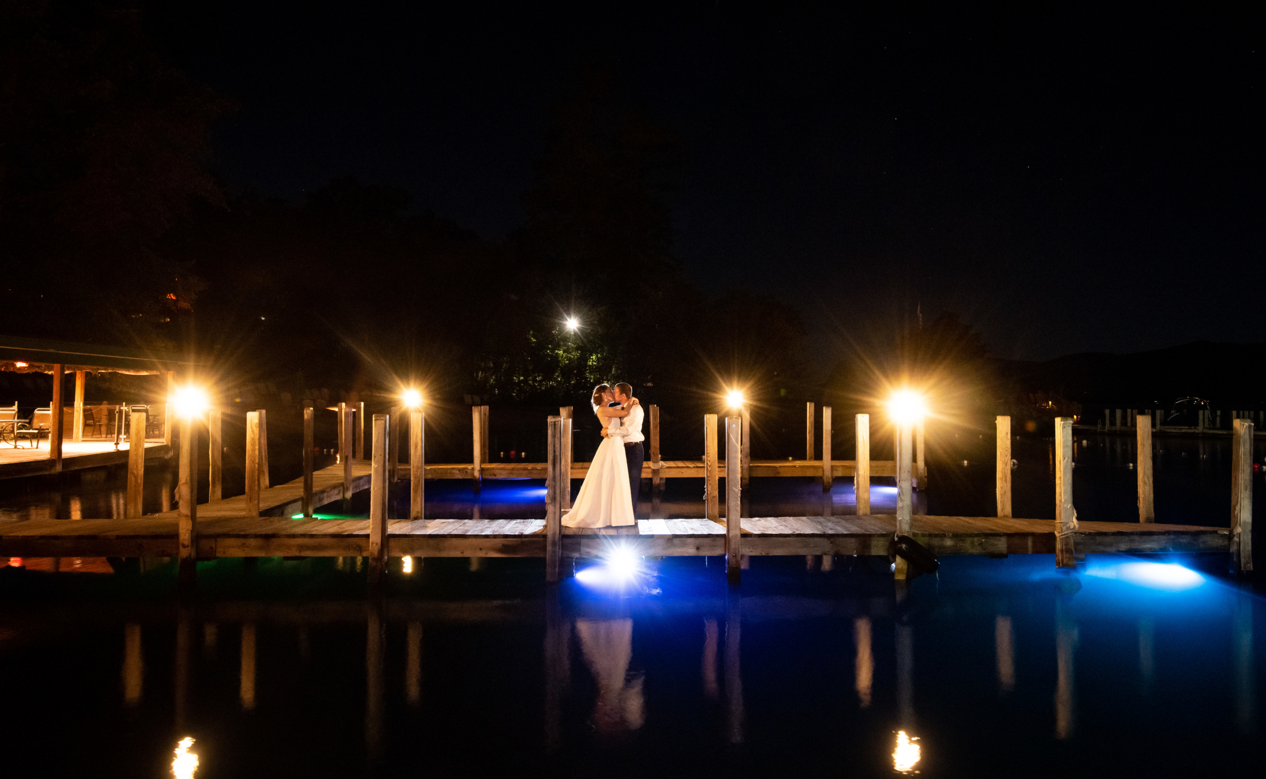 Bride and Groom kissing on pier at night.