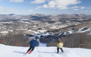 People skiing down a mountain at one of the upstate new york ski resorts near Lake George